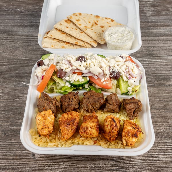 Tony's Gyros Greek Cuisine takeout container with chicken and beef skewers, rice, Greek salad, pita, and tzatziki.