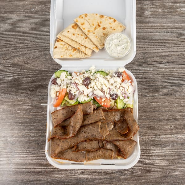 Tony's Gyros Greek Cuisine takeout container with sliced gyro meat, Greek salad, pita bread, and tzatziki.