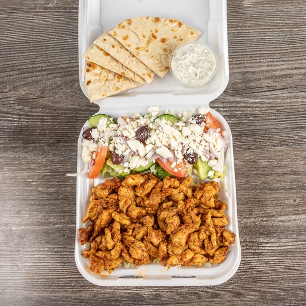 Tony's Gyros Greek chicken entree with Greek salad, pita bread, and tzatziki sauce in a takeout container.